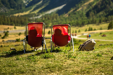 Zwei Wanderer sitzen in roten Liegestühlen und relaxen