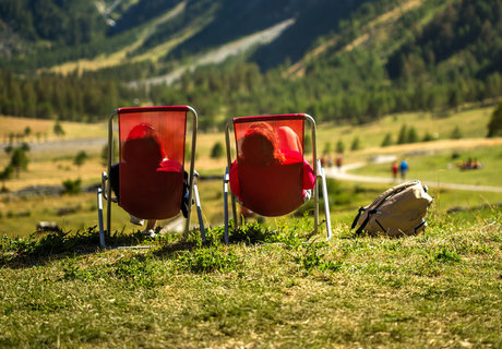 Zwei Wanderer sitzen in roten Liegestühlen und relaxen